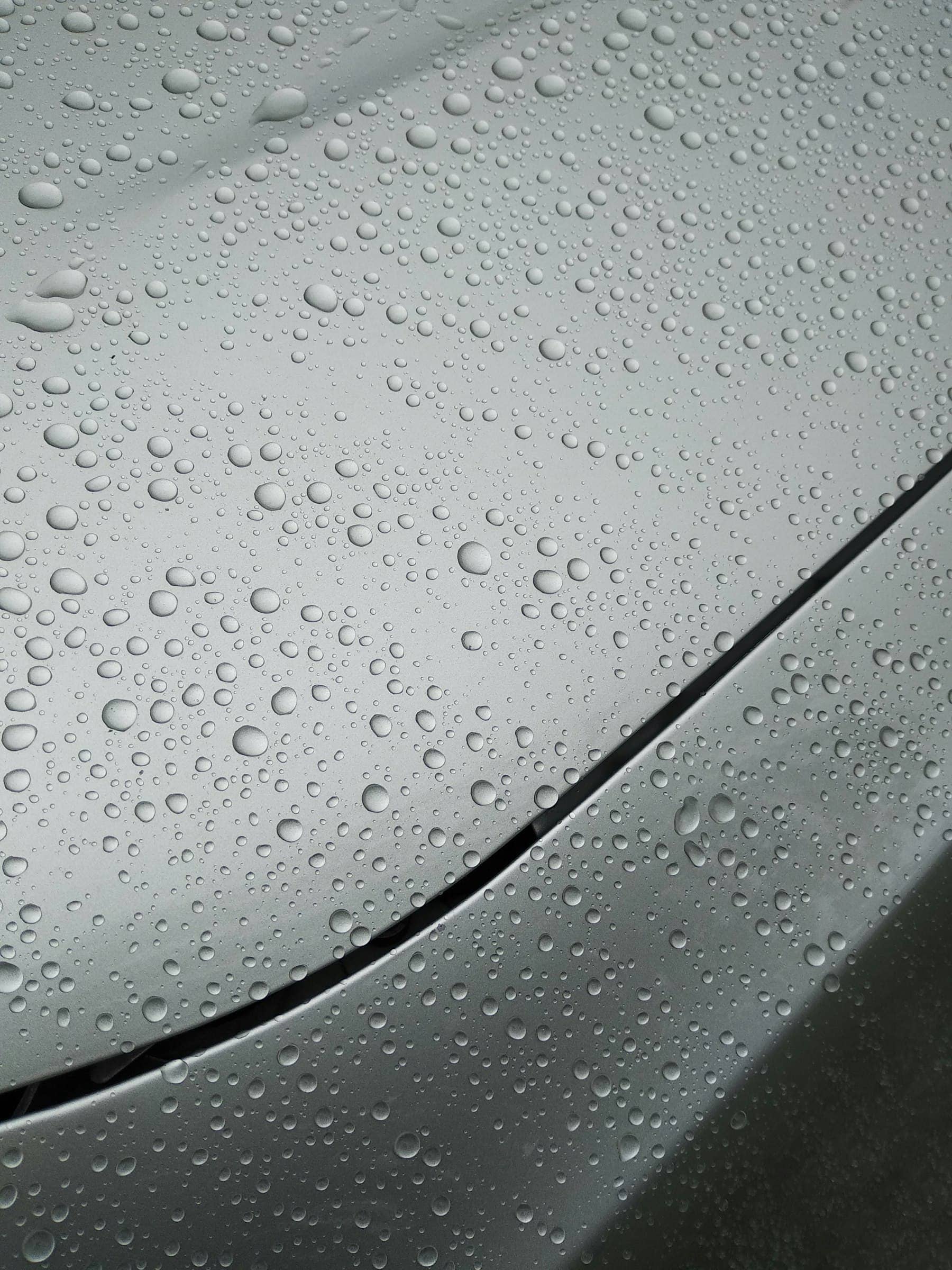 Water beading on a coated metallic grey car bonnet