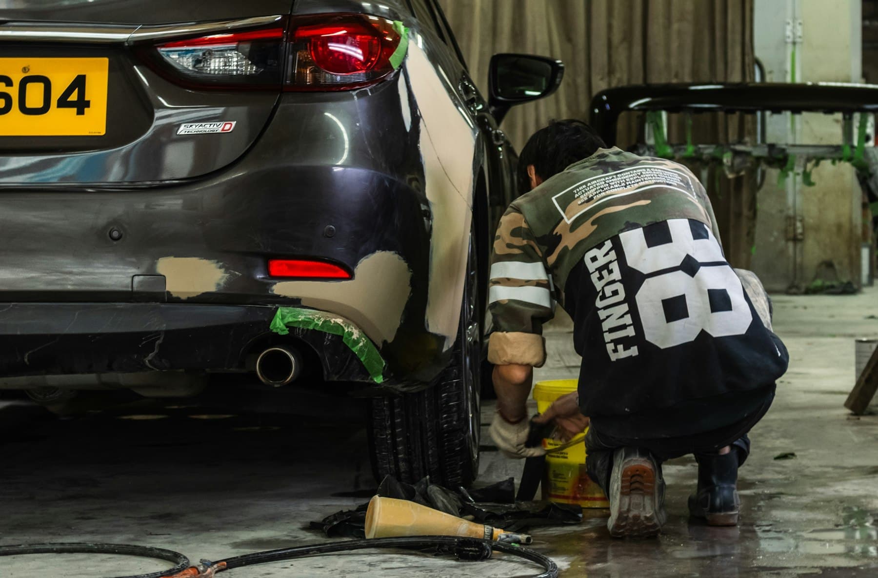 Technician repairing the rear bumper of a car in a workshop