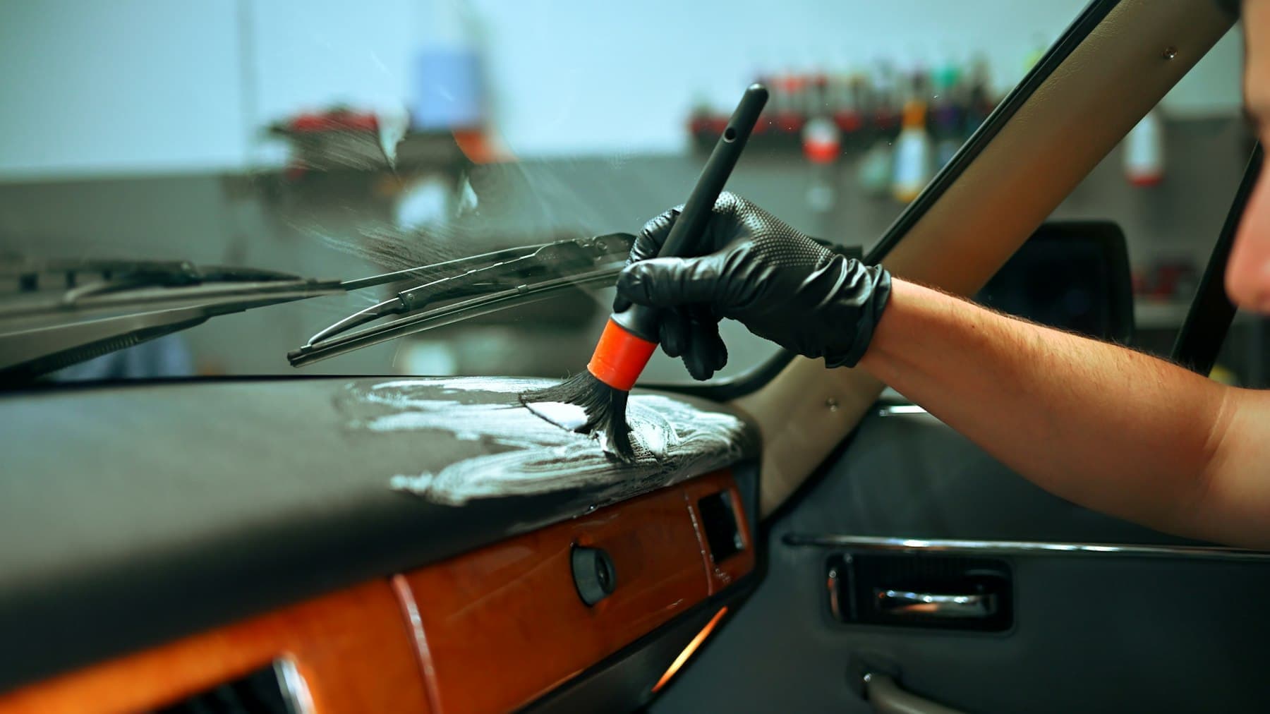Detailer cleaning a car dashboard with a soft brush
