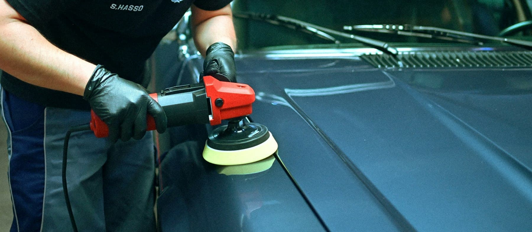 Polishing a blue car bonnet with a dual-action machine polisher