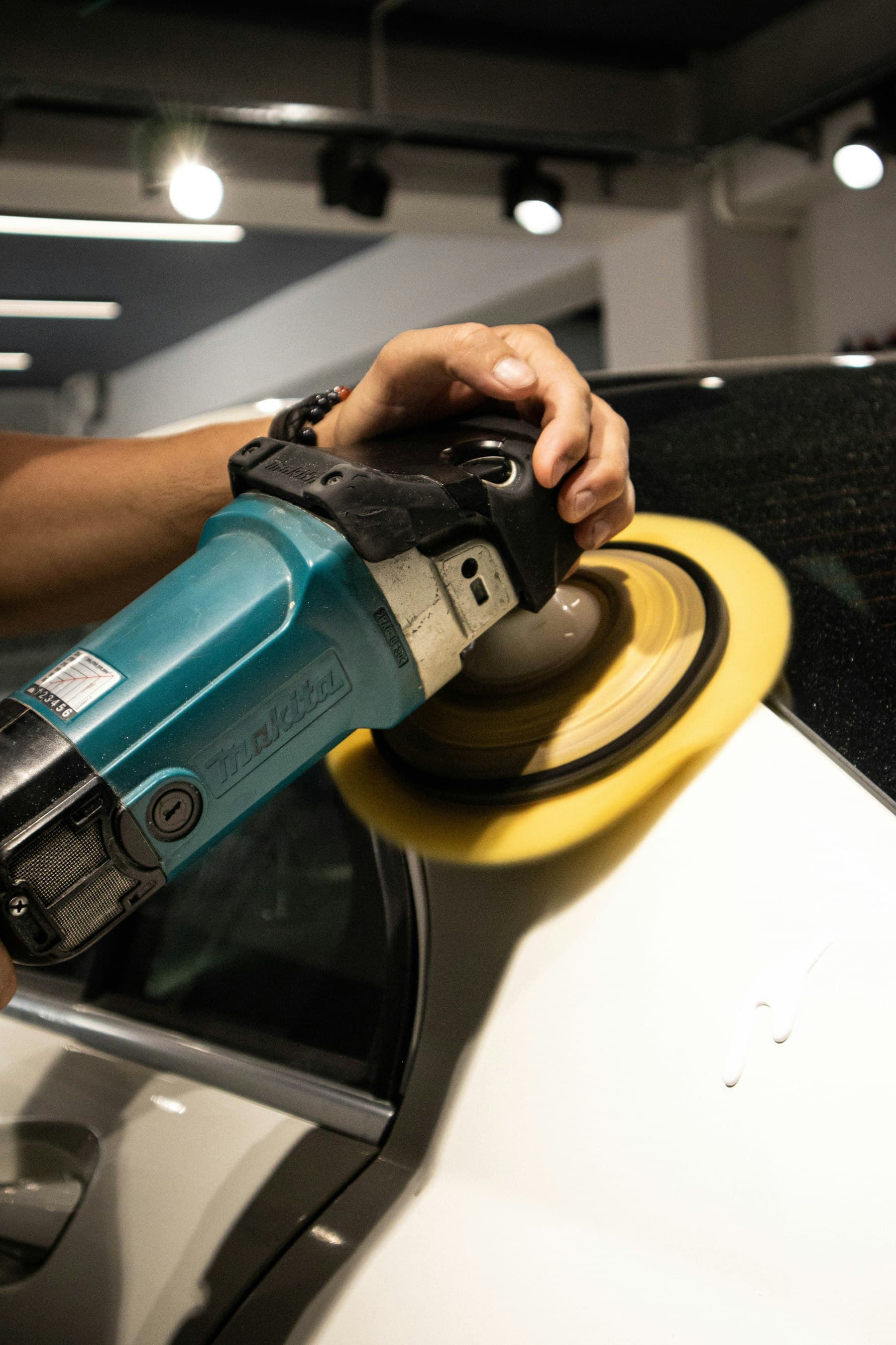 Rotary polisher with a yellow pad working on white paint